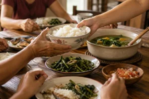 Hands sharing a bowl of rice at a family meal.